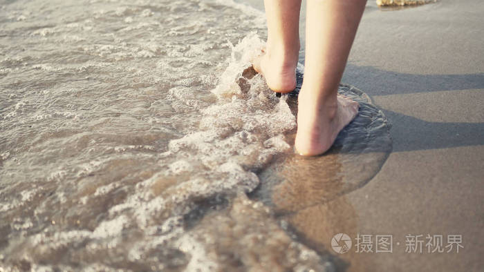 在海上行走的女性赤脚腿的特写镜头被海浪拍打