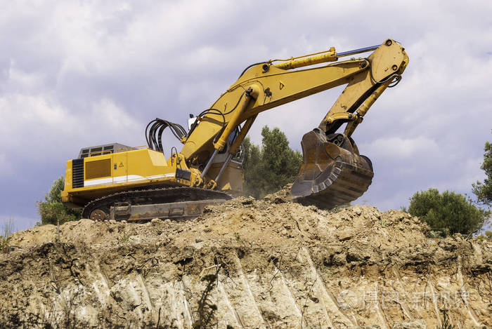 施工现场的黄色挖掘机正在准备将土壤装入自卸汽车中.