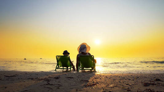 一家人母子在日落时分坐在沙滩上玩得开心