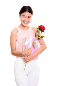 年轻快乐的亚洲女人微笑着拿着红玫瑰和礼物