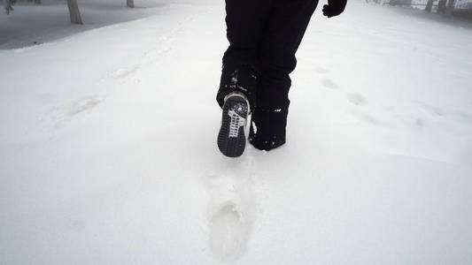 在深雪的山上行走的女人的脚