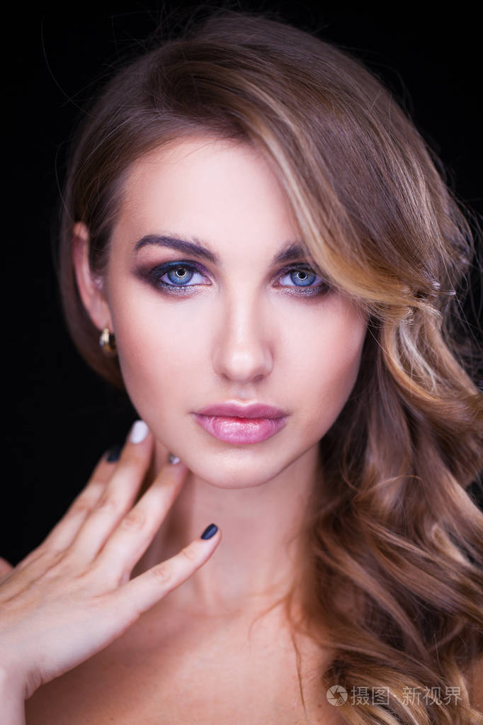 在黑色背景上留着金色长发的漂亮模特的特写肖像.