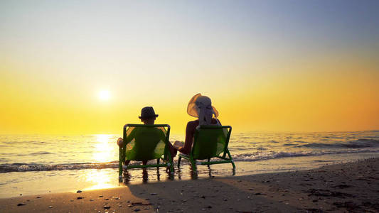 快乐的家庭母子带着帽子在暑假期间在海滩上享受豪华的日落。 旅行概念