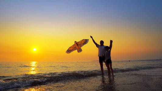 一个小男孩和爸爸玩在日落时放风筝的暑假概念