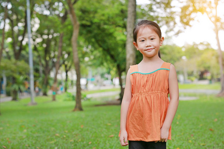微笑的亚洲小女孩在自然公园的肖像与看相机。