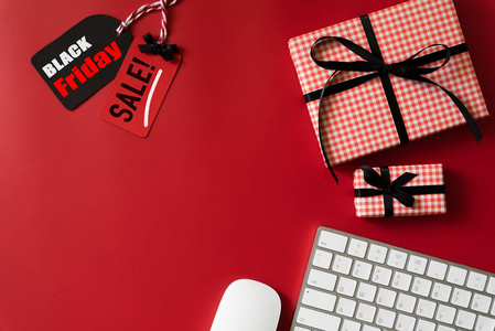 黑色星期五销售文本的红色和黑色标签与闹钟键盘电脑和礼品盒红色背景。 购物概念。