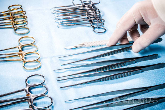 手术姐姐拿着桌子上的镊子和工具,在手术过程中向外科医生申请.