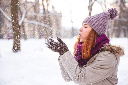 愉快的红头发的妇女走在冬季公园和享受雪