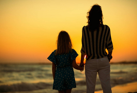 晚上在海滩上闲暇时母女眺望远方的背影照片