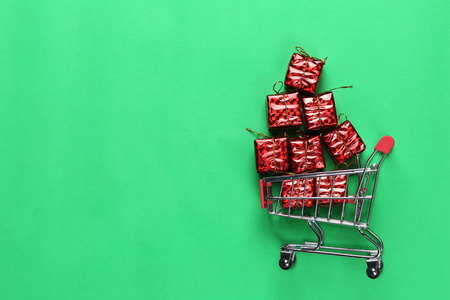 红色礼品盒圣诞装饰在购物车上，并有复制空间跳跃在节日和新年。