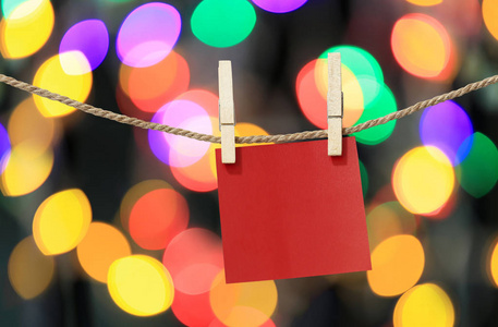 空白的红纸笔记挂在晾衣绳上，用于圣诞节的设计，在Bokeh光背景记事本上，用于重要一天的设计思路。