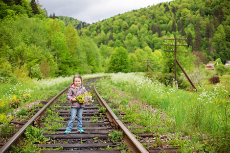 铁轨上有花束的可爱小女孩的肖像