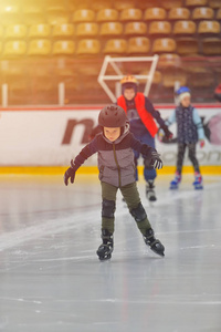 可爱的小男孩穿着冬天的衣服，在溜冰场上滑冰
