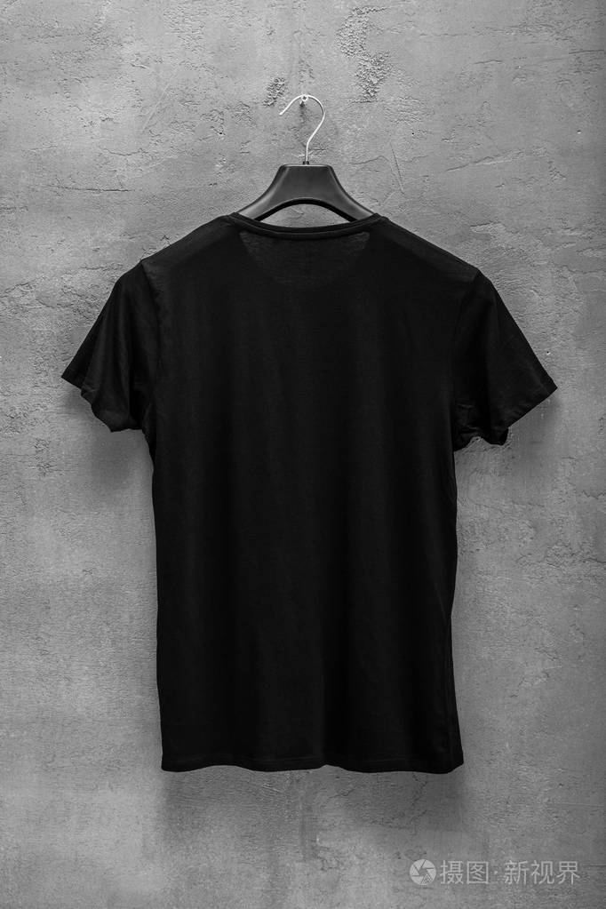 背面的男性黑色棉t衬衫在衣架和混凝土墙的背景t恤没有印花