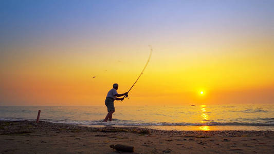 一个活跃的渔夫在日落时分投掷渔具的剪影