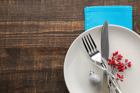 圣诞餐桌设置。 带蓝色餐巾的刀叉和盘子。 在棕色的木桌上。 顶部视图，空间为铭文。 新年。 假日