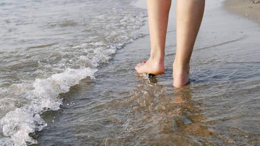 水上行走在赤脚的女性脚下行走,溅在海水上,电影中的稳定镜头照片