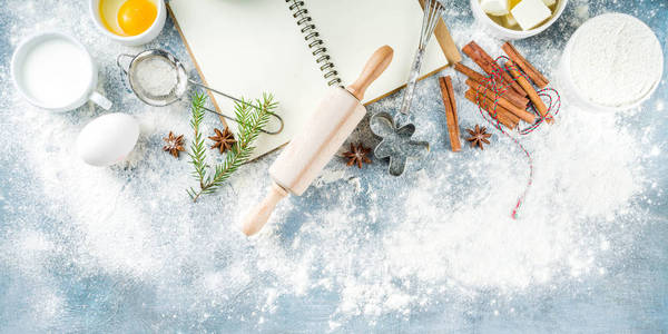 圣诞节和冬季烘焙背景。 厨房用具和烹饪原料，烘焙面粉，糖，鸡蛋，黄油，牛奶，肉桂棒，搅拌，擀面杖，蓝色，混凝土背景，复制空间，俯