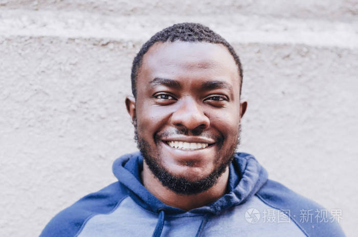 一个黑人的肖像特写在一件运动毛衣的背景上的条纹明亮的墙开朗积极的