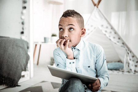 愉快的体贴的男孩看着天花板照片