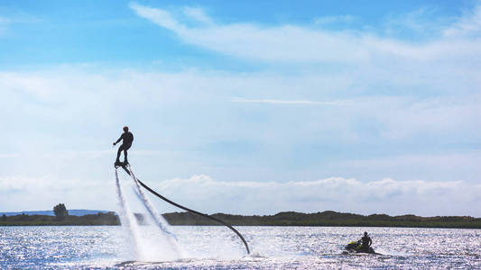 在阳光明媚的日子里，一个人正骑着一只飞板在湖上