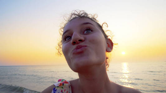 年轻青少年手持相机，日落时在海滩上翻车的自拍