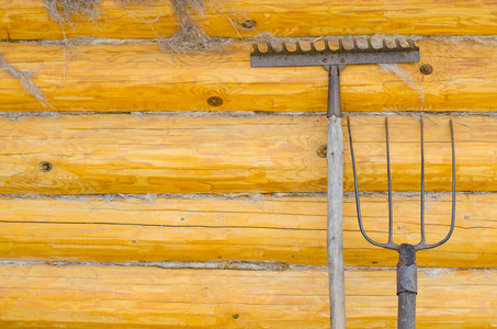旧叉子耙。 背景黄色木制墙壁由原木制成。 近点