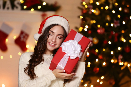 戴圣诞帽的年轻女子，家里圣诞树附近有礼品盒