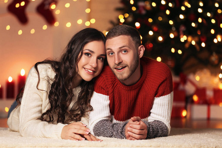 年轻夫妇躺在家中圣诞树旁