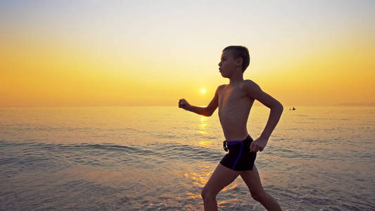 特写小男孩跑步，在海边与日落慢跑