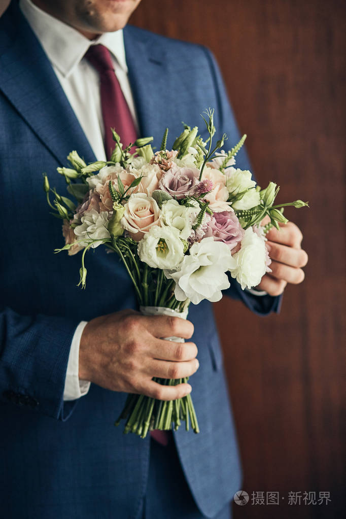 男人手捧新娘花束新郎在婚礼前的早晨准备好