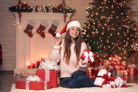 小女孩坐在家中圣诞树旁的礼品盒里