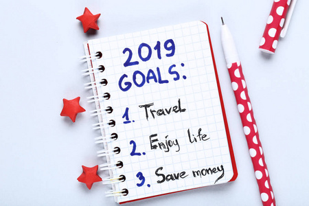 将2019年的目标写在笔记本上，灰色背景上有纸笔星