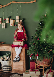 穿着勃艮第服的女孩在乡村客房装饰圣诞树