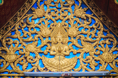 美丽的金色山墙小教堂，雕刻着天使雕塑。 泰国寺庙的山墙顶部装饰了一尊天使雕塑。