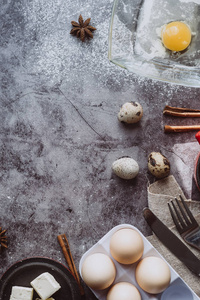 健康的烘焙原料。 勺子与面粉菜肴，鸡蛋，黄油，盐和擀面杖在灰色背景。烘焙背景框架。 顶部视图复制空间。