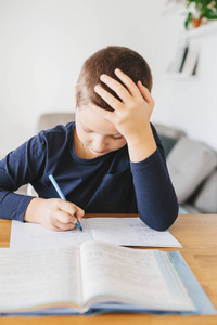 小学生在家里的桌子上做作业。 家庭教育概念