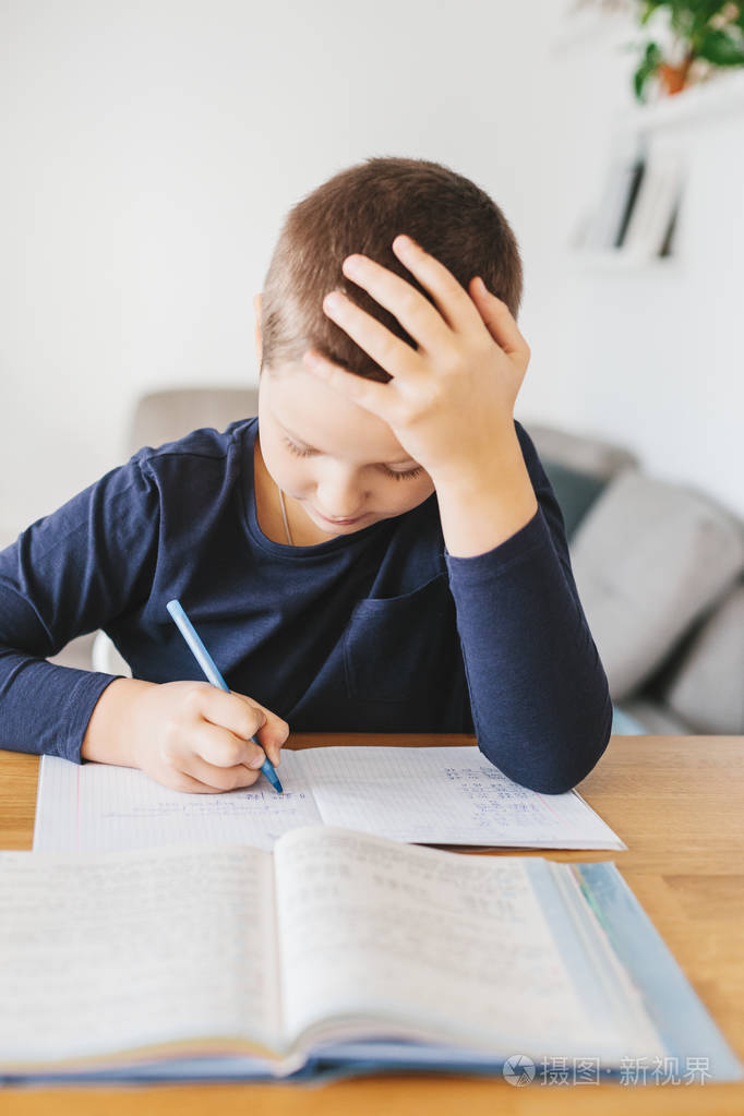 小学生在家里的桌子上做作业. 家庭教育概念照片-正版商用图片14lsty-