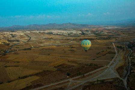 土耳其卡帕多西亚太阳升起时，热气球在土耳其卡帕多西亚地区飞行。气球在蓝天的映衬下飞行，五彩缤纷的娱乐交通形式，在空中飞行的气球