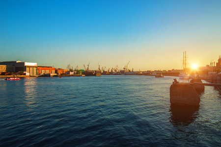 美丽的黄昏日落可见港口起重机和船只在涅瓦河圣彼得堡俄罗斯港口。 瓦西里耶夫斯基岛。
