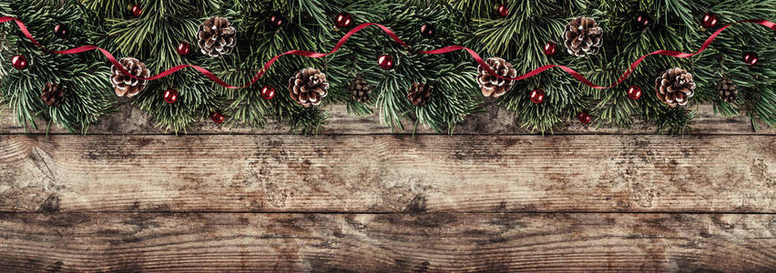 创意布局框架由圣诞杉枝松果和红色装饰在木制背景。 圣诞节和新年主题。 平躺式顶部宽幅构图