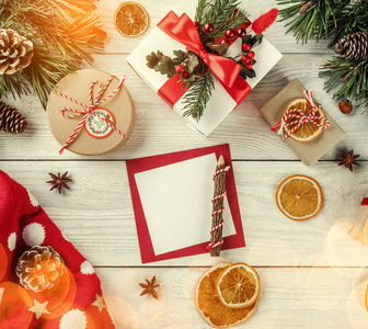创意布局框架由圣诞树树枝纸卡音符松果礼品圣诞毛衣白色木制背景制成。 圣诞节和新年主题。 平躺式顶部视图