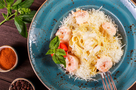 意大利面与虾，奶酪，帕尔马西红柿，罗勒和奶油酱在黑暗的木制背景意大利菜。 桌子上的配料。 顶部视图