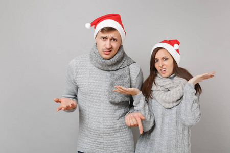 快乐有趣的夫妇女孩男子红色圣诞帽灰色毛衣围巾隔离在灰色墙壁背景工作室肖像。 新年快乐，2019年庆祝节日聚会的理念。 模拟复制空