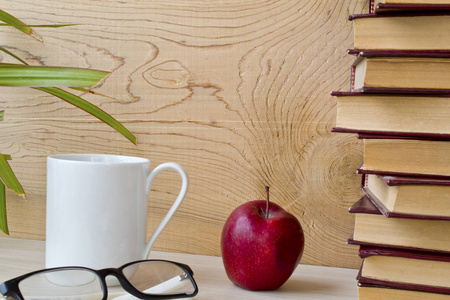 旧书眼镜，苹果和咖啡，背景是木制的。
