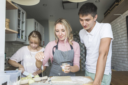幸福的家庭正在家里的厨房里准备一个馅饼。幸福家庭和家庭舒适的概念