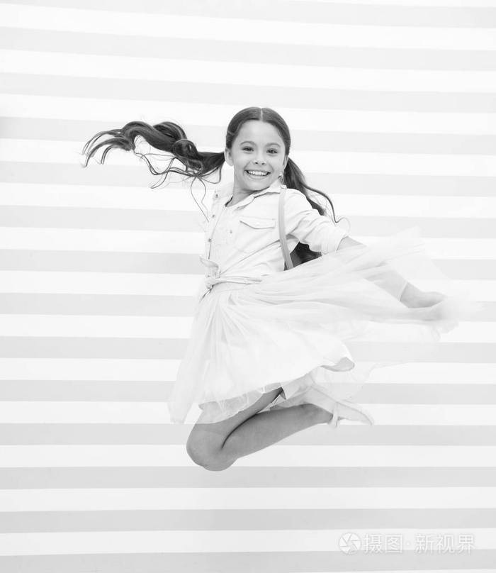 充满活力女孩快乐的脸马尾辫的发型在空气中跳跃小女