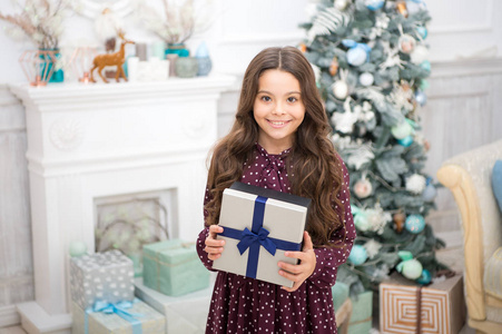 圣诞节就要到了。可爱的小女孩收到了节日礼物。最好的圣诞礼物孩子为打开她的礼物而兴奋。孩子小女孩在典雅的礼服和礼物盒圣诞树背景