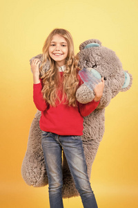 女孩拥抱大泰迪熊在橙色背景图片