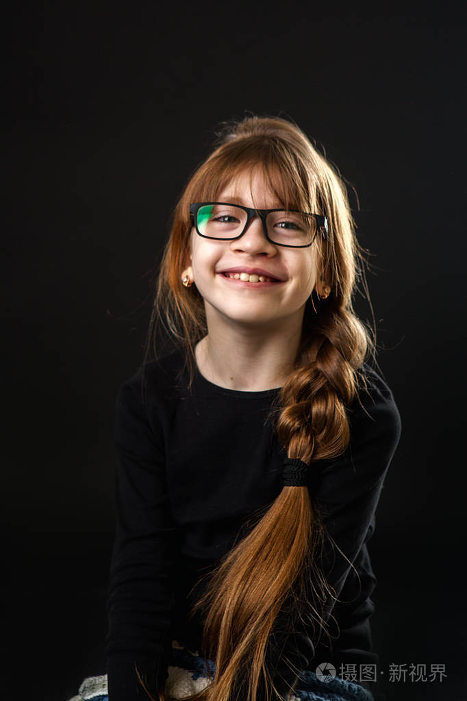 戴眼镜的小女孩笑了笑.黑色背景,大人像.